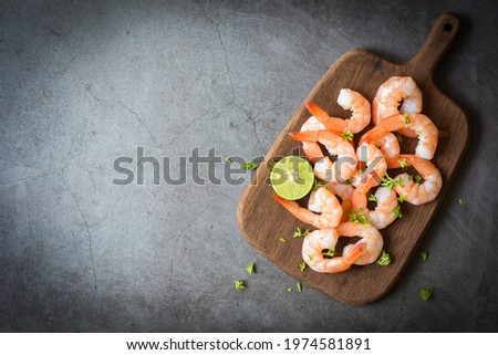 Fresh shrimps prawns seafood lemon lime with herbs and spice, Shrimp peeled on wooden cutting board dark background dining table food, top view