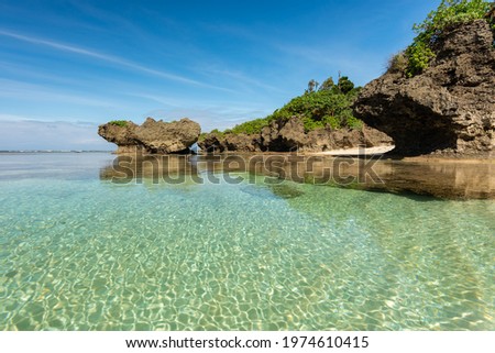 Gorgeous paradise beach, crystalline emerald green sea pool, coastal rocks, hidden cliff side beach, blue sky. Iriomote Island, natural world heritage.  Royalty-Free Stock Photo #1974610415