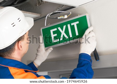 foreman completes installation of lighting signs emergency exit