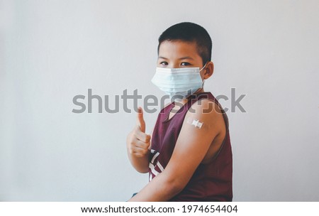 Asian boy wearing protective mask against covid-19 with showing her arm after getting vaccine. Royalty-Free Stock Photo #1974654404