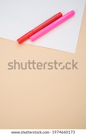 A closeup shot of markers with white paper isolated on a pink background with copyspace
