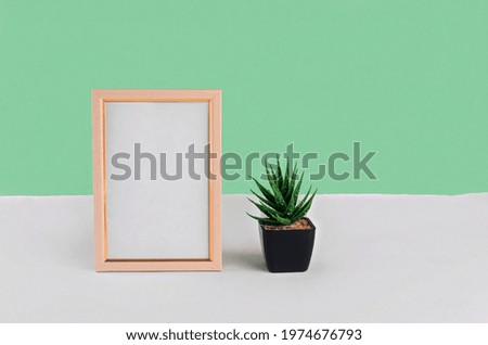 Blank white vertical photo frame mockup. White table and green wall background. Minimalist concept with place for text. Mock up with decor elements.