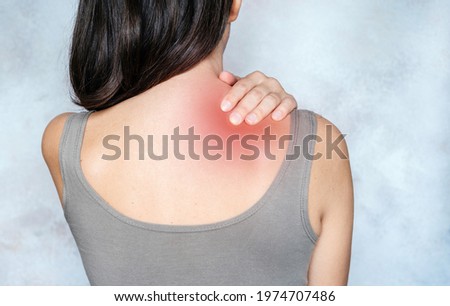 A woman massages her shoulder and neck pain points, trigger point massage, physiotherapy, and massage concept Royalty-Free Stock Photo #1974707486