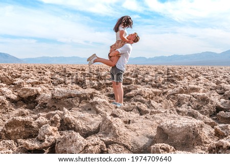 A beautiful young tourist couple a man and a woman embrace on the Devil's Golf course in Death Valley