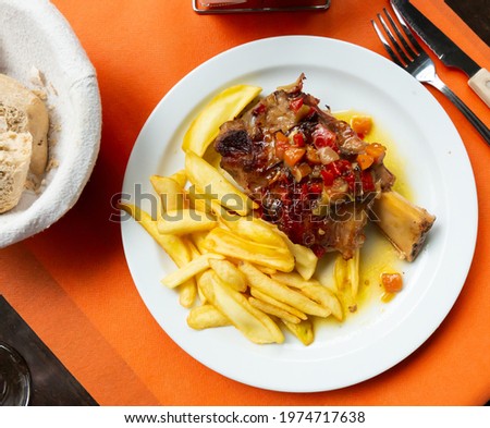 Image of pork baked shank with vegetables and french fries served at plate