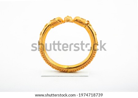Golden bangle with beautiful work close view ideal for wedding isolated on white background. Gold jewellery stock photo. Royalty-Free Stock Photo #1974718739