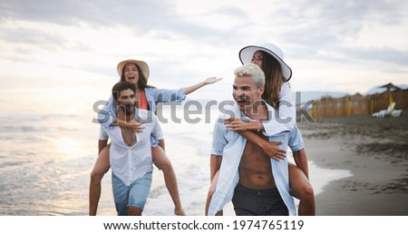 Happy boyfriends piggybacking their girlfriends at beach