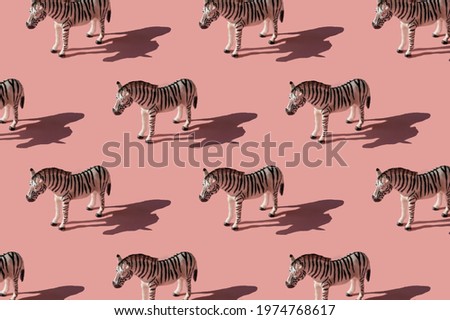 Pattern made with zebra toy on pink background. Trendy minimal picture with hard  sunlight shadows.