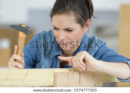 woman nursing sore finger after hurting it with a hammer