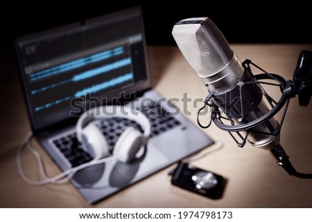 Podcast microphone, laptop computer camera and headphones on desk in recording studio Royalty-Free Stock Photo #1974798173
