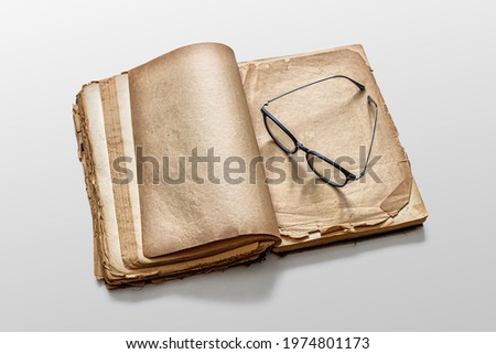 An old book with yellowed pages, glasses left by the reader, lie on a white background in the library