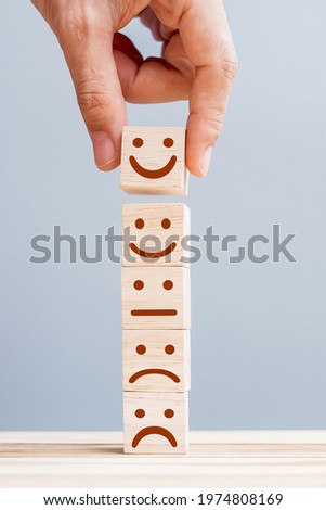 Hand holding smile face symbol on wooden cube blocks. Emotion, Service rating, ranking, customer review, satisfaction and feedback concept