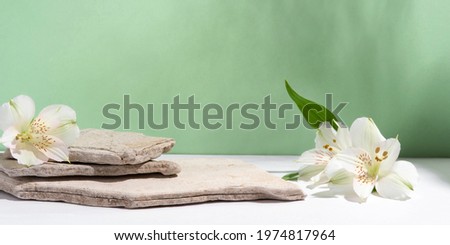 Background for cosmetic products of natural green color. Stone podium with white flowers. Front view.