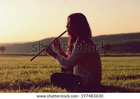 Indian girl playing a flute at sunset