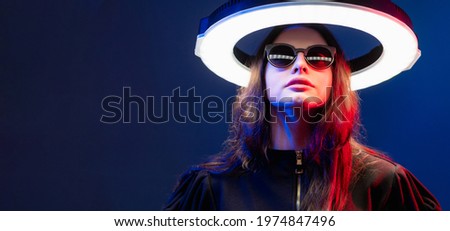 Cyberpunk woman. Futuristic banner. Quantum technology. Red neon light female cyborg in sunglasses with white glowing LED circle halo isolated on dark blue copy space background.