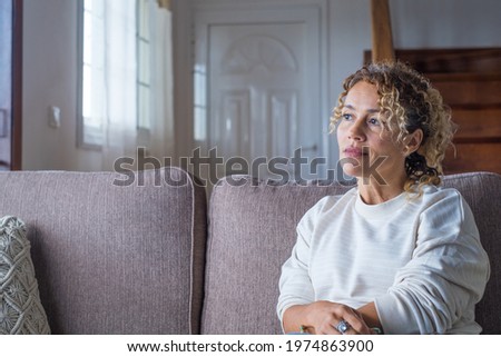 Thoughtful pensive girl sitting alone looking through window thinking of problem or reflecting, anxious melancholic young woman serious face lost in thoughts feel lonely doubtful worried, side view Royalty-Free Stock Photo #1974863900