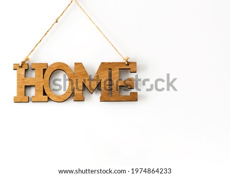 Home wood decorative lettering hanging on a white wall. Home Interior and copy-space