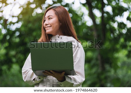 A young woman holding and using laptop computer in the outdoors