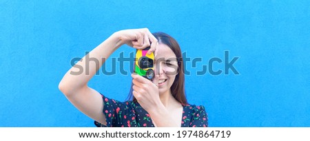 Funny caucasian girl in casual outfit is taking a pictures with a vintage camera outdoor - Summer, joy, relax, concept - close up portrait, coloured background with a space for advertising