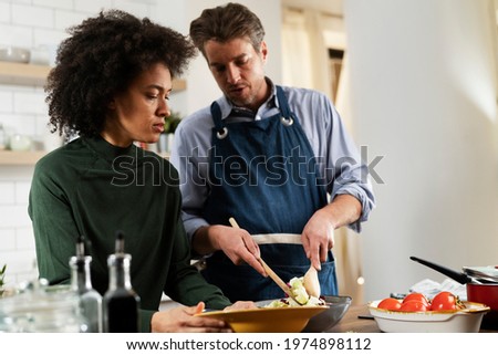 Happy smiling couple cooking together. Beautiful woman with curly hair enjoying in kitchen with her husband
