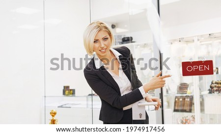 Attractive saleswoman at the door of her shop