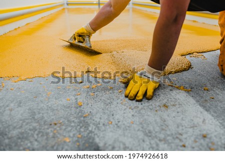 Worker applying epoxy and polyurethane flooring system.These easy-to-clean products also have non-slip features. Royalty-Free Stock Photo #1974926618