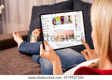 Woman browsing social media website on tablet computer at home Royalty-Free Stock Photo #1974927326