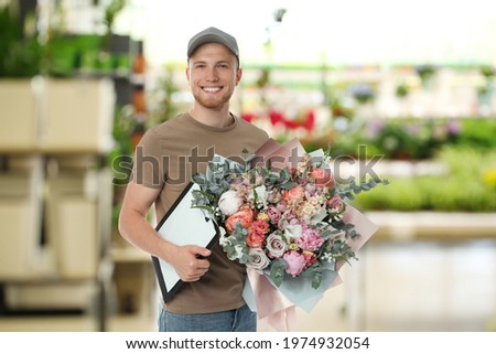 Delivery man with beautiful bouquet in flower shop 
