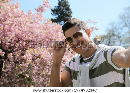 Happy handsome man taking selfie in park