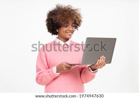 Studio portrait of smiling african american teen girl, high school or online course student holding laptop, isolated on gray background