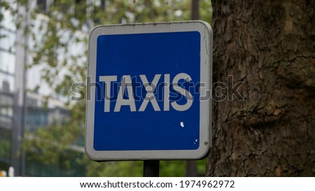 Close up of a French "taxis" sign next to a tree at a taxi stop in Paris, France