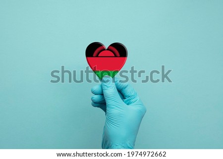 Hands wearing protective surgical gloves holding Malawi flag heart