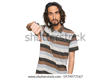 Young hispanic man wearing casual clothes looking unhappy and angry showing rejection and negative with thumbs down gesture. bad expression. 