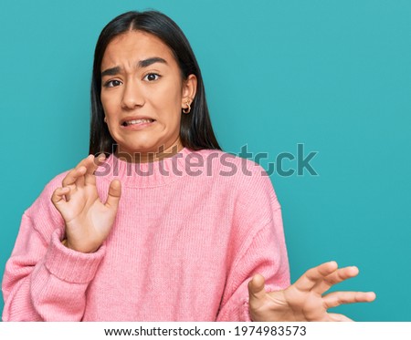 Young asian woman wearing casual winter sweater disgusted expression, displeased and fearful doing disgust face because aversion reaction.  Royalty-Free Stock Photo #1974983573