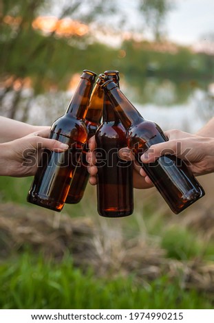 Bottles with beer in the hands of young people in nature. Selective focus. Nature.