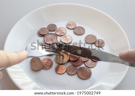 Pile of euro coins lie on a plate. Male hands hold cutlery to start eating a dish. Eat savings, consumer savings concept, eating savings. Consumer savings concept