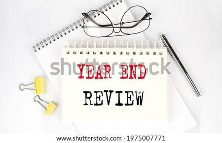 YEAR END REVIEW text on notebook with pen,clips and glasses