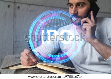 Handsome analyst in casual long sleeve talking phone, taking notes at office workplace try to analyze IPO project. Double exposure. Initial public offering hologram. Royalty-Free Stock Photo #1975016714