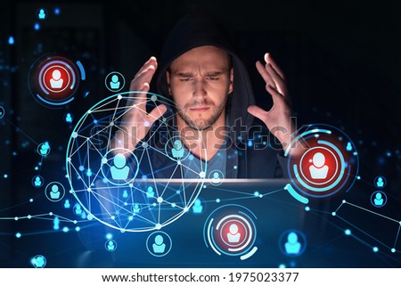 Handsome businessman in hoodie at workplace working with laptop to hire new employees for international business consulting. HR, social media hologram icons over office background