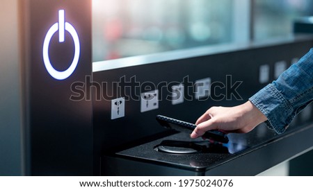 Male hand putting smartphone on wireless charger or induction charger. Mobile phone power charging service station in public area. Royalty-Free Stock Photo #1975024076