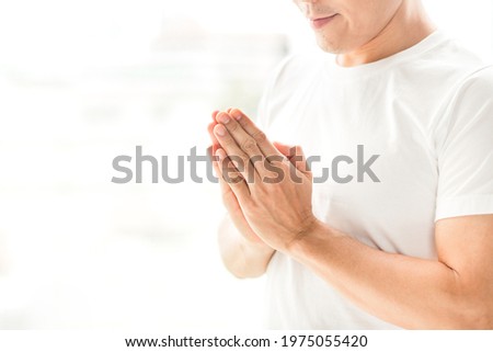 Praying hands of Asian man in white t shirt on white background. Royalty-Free Stock Photo #1975055420