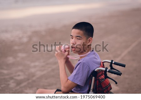 Asian special child on wheelchair on the beach with parents in family holiday to travel, exercise and learning about nature around the sea beach, Life in the education age, Happy disabled kid concept
