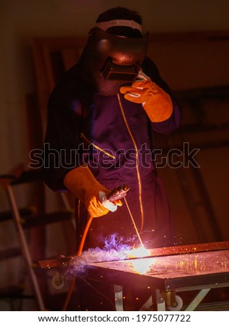 Image of a welded steel plate welding in an industrial factory. He wears complete protective equipment such as masks, gloves, welding suits. This kind of work requires specific skills Royalty-Free Stock Photo #1975077722