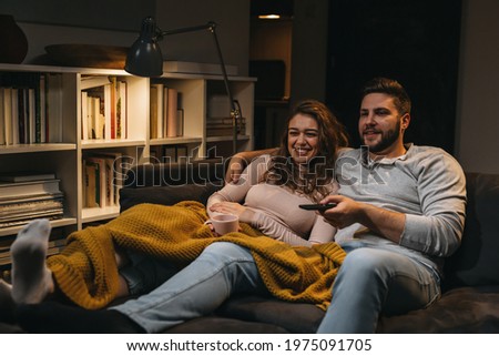 couple laying on couch at home watching tv