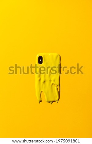 Yellow smartphone melting against a yellow background