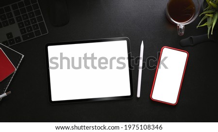 Digital tablet, smart phone, coffee cup and notebook on black leather.