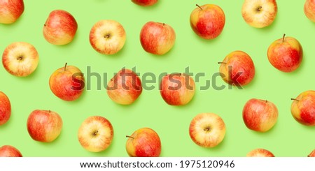 Red apple fruits over green backdrop seamless texture. Flat lay background