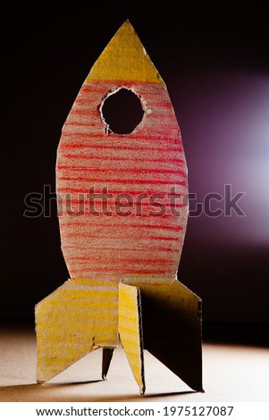 Rocket made of cardboard on a dark background. Children art project. DIY concept. Cardboard craft.