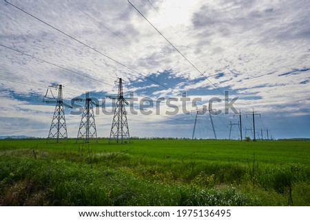 in the green field high-voltage power lines during the day. power distribution station. high voltage power tower horizontal photo
