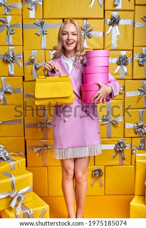 Gorgeous Blonde Adult Woman Celebrating Holiday, Holding Gift boxes In Hands, Fashionably Dressed Woman With Handbag Smiling Broadly, Congratulating Or Receiving Presents